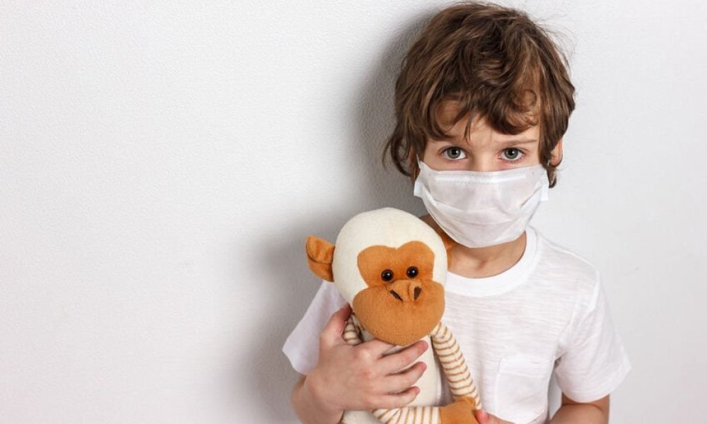 Portrait of kid wearing medical mask with toy monkey on white background. Concept of coronavirus quarantine or covid-19.Protection against virus and infection control concept.